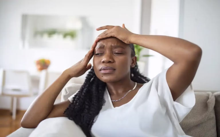 portrait young black girl sitting couch home with headache pain beautiful woman suffering from chronic daily headaches sad woman holding her head because sinus pain